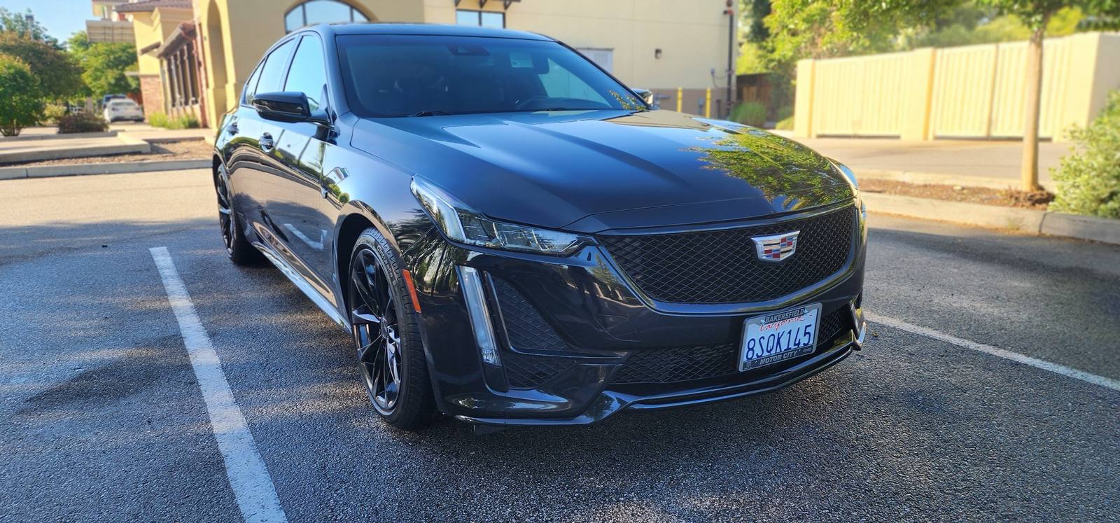 Glossy black Cadillac CT5 sedan freshly detailed in a parking lot