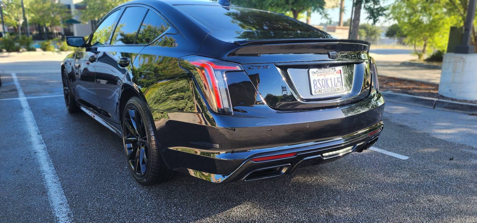Glossy black Cadillac CT5 rear exterior detail in parking lot showing reflective paint