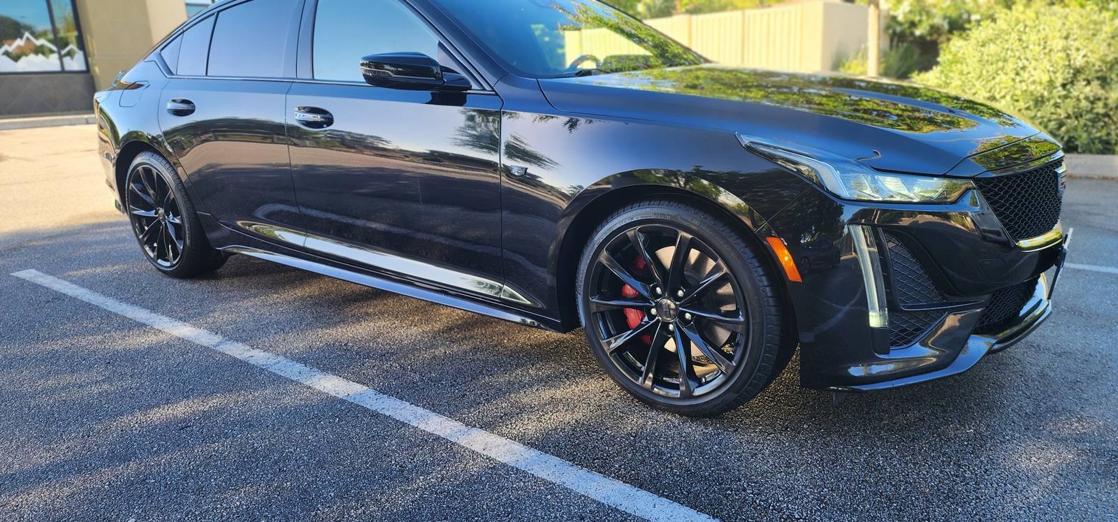 Glossy black Cadillac CT5 sedan with red brake calipers after professional exterior detail