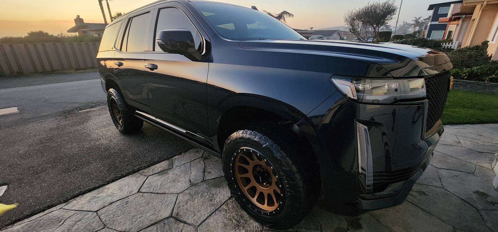 Black Cadillac Escalade with bronze off-road wheels after professional exterior detail